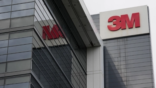Red 3M logo mounted on a modern glass office building exterior alongside another corporate office building