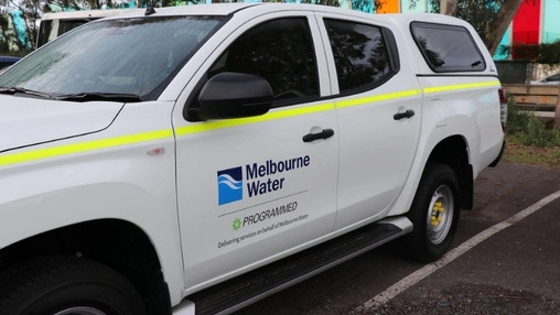 Melbourne Water and Programmed branded white utility vehicle with yellow stripe parked in an outdoor car park
