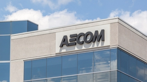 Close-up of AECOM signage on a corporate office building with blue glass curtain wall and partly cloudy sky
